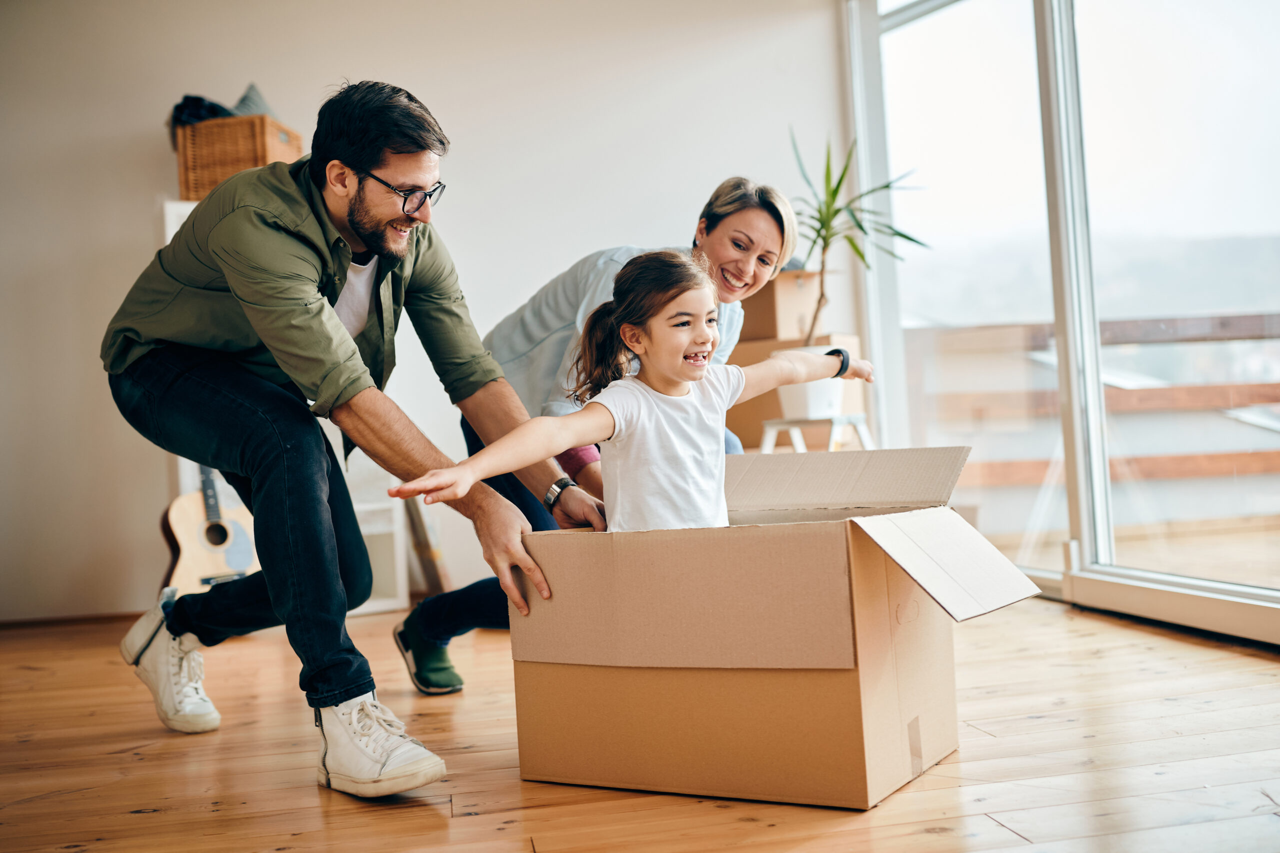 happy daughter having fun with her parents while relocating new apartment scaled